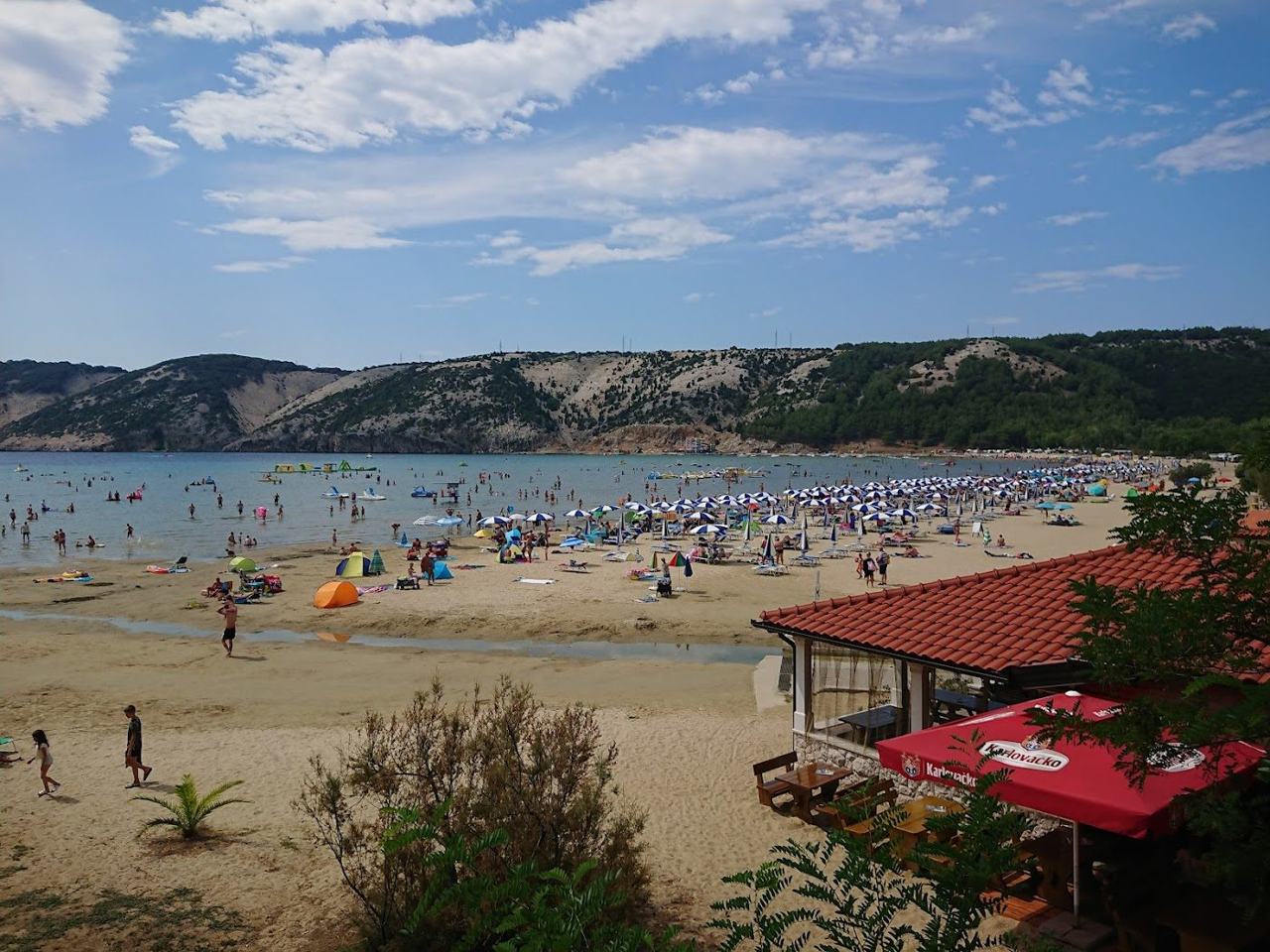 Golden sand and shallow turquoise water at Paradise Beach in Lopar on Rab