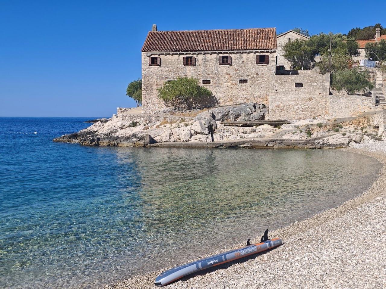 Dubovica pebble cove south of Hvar town with turquoise water and a single old stone house on the Dalmatian Coast