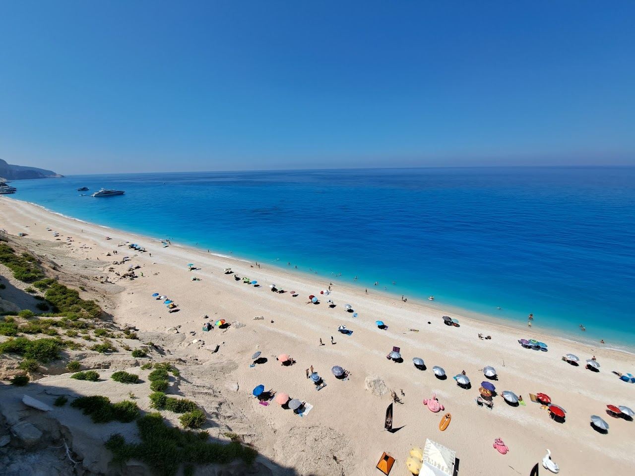 The pale shore and bright blue sea of Egremni beach seen below the steep cliffs of southwest Lefkada