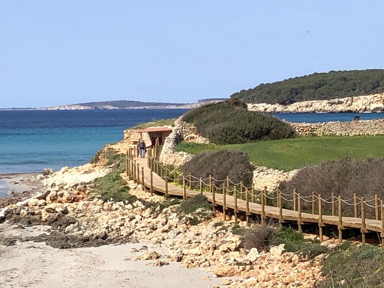 Pale gold sand and shallow water along Sant Tomas beach on the south coast of Menorca