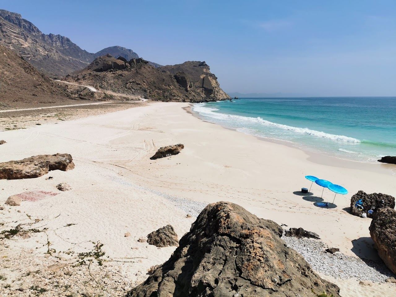 Tall cliffs above an empty pale cove and clear water at Fazayah beach west of Salalah