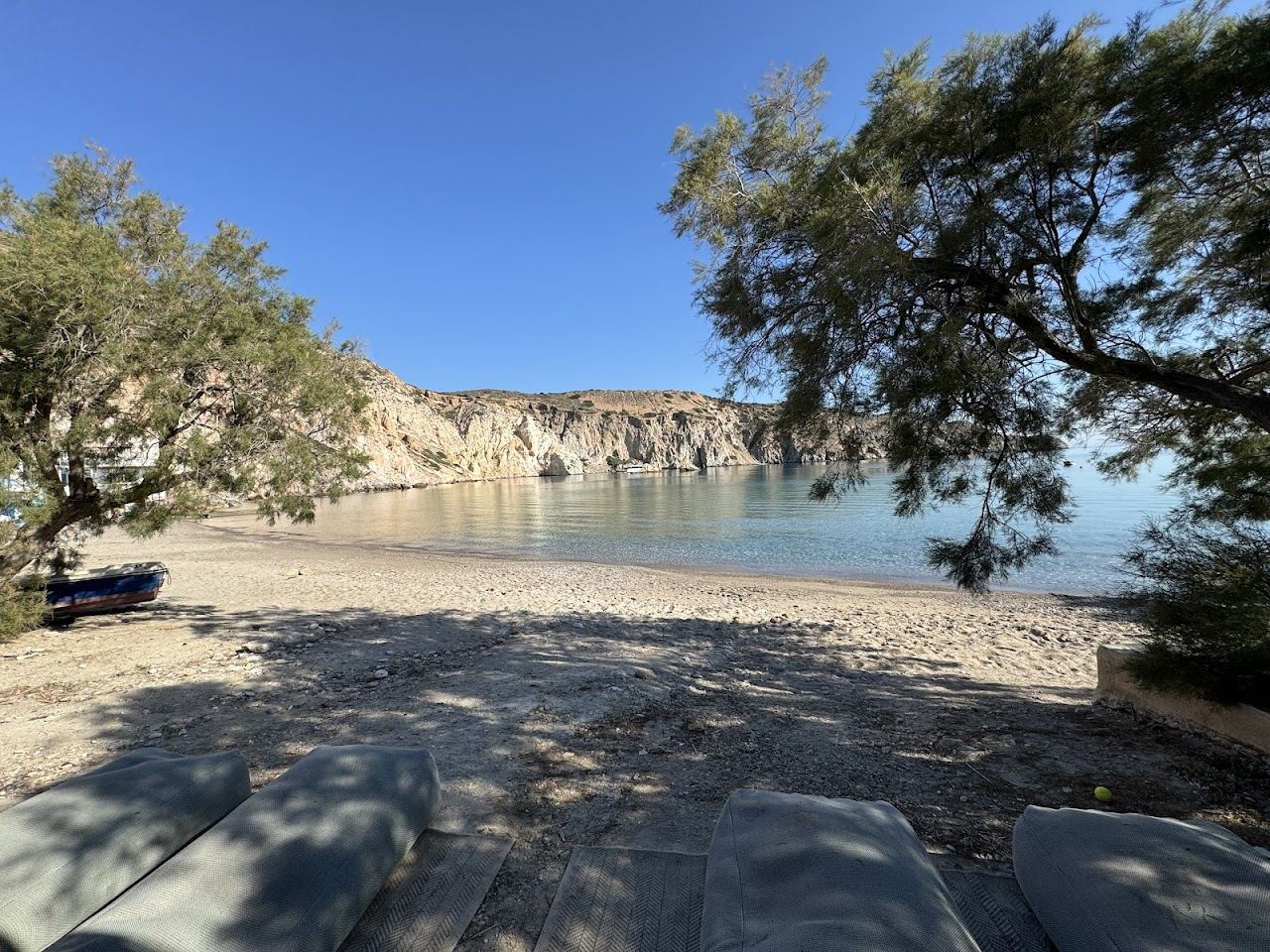 White fishing boat houses and the small calm beach of Firopotamos with no beach club on the north coast of Milos