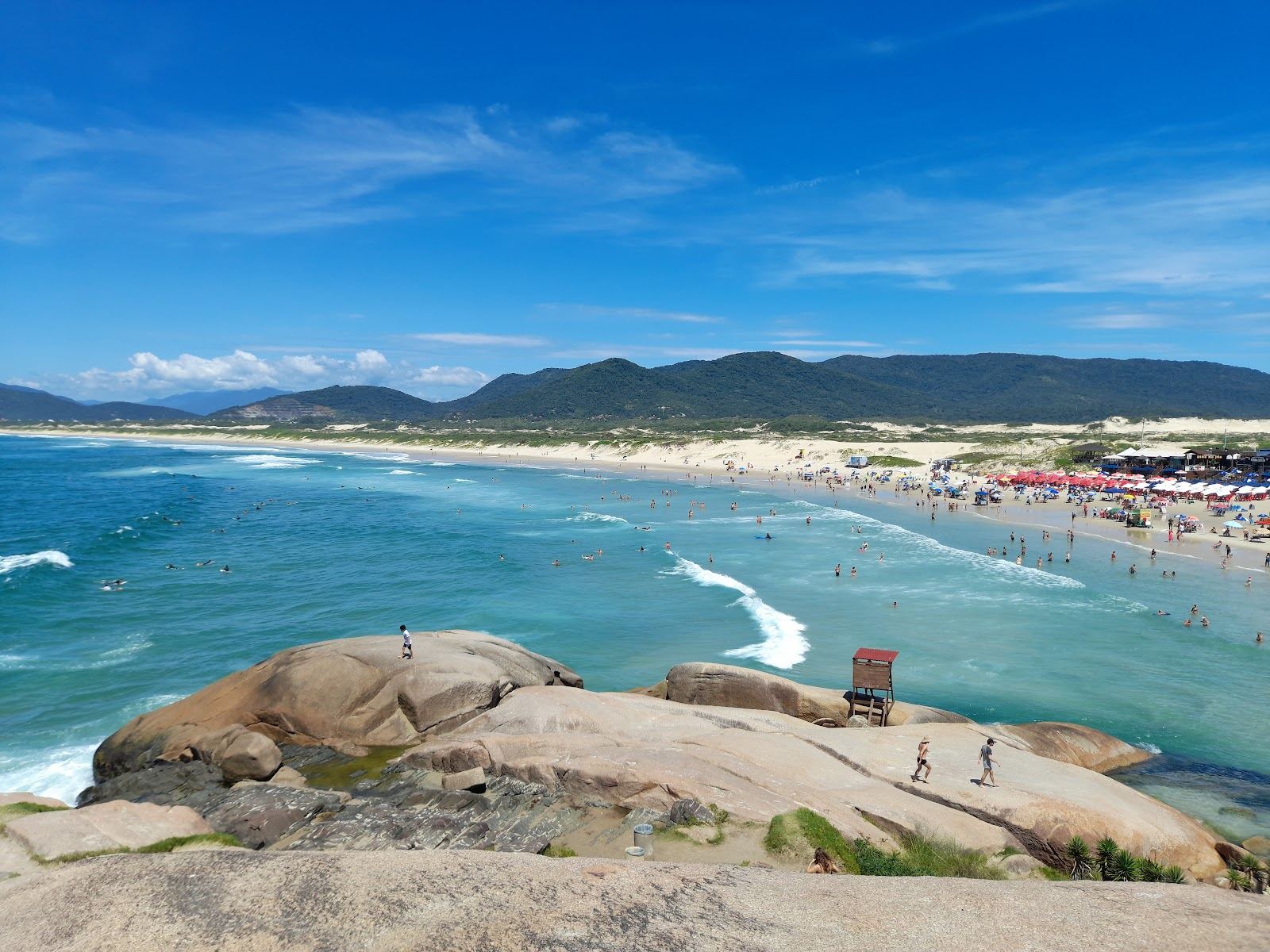 Surf rolling into the wide sweep of Joaquina beach with dunes behind on Florianopolis