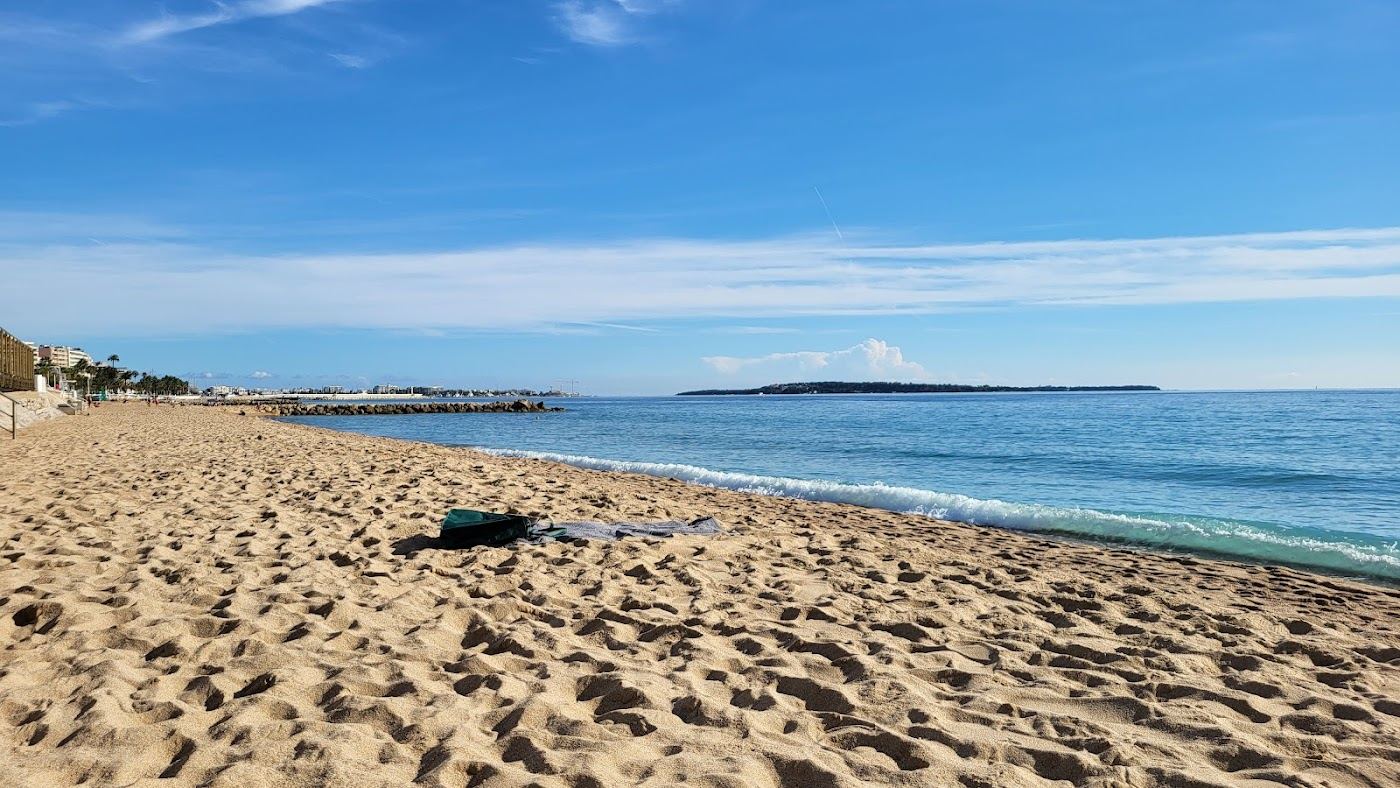 Free public sand and clear sea at a French Riviera beach with the town behind