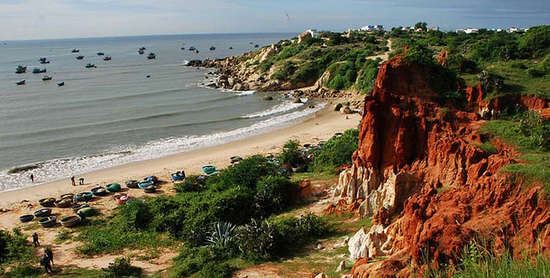 The bright red clay cliffs and blue green water of Ganh Son Beach near Mui Ne