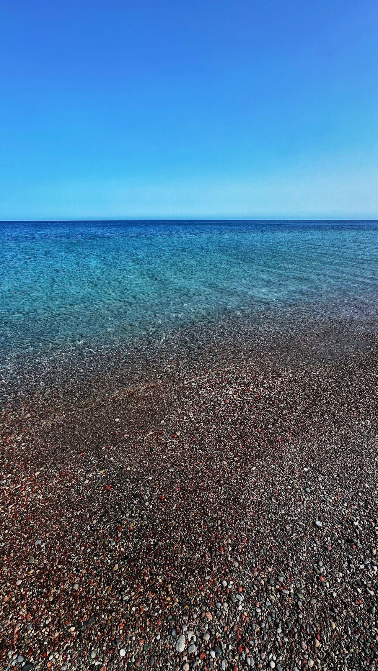 Long quiet stretch of pebble and open sea at Gennadi beach on the undeveloped southeast coast of Rhodes