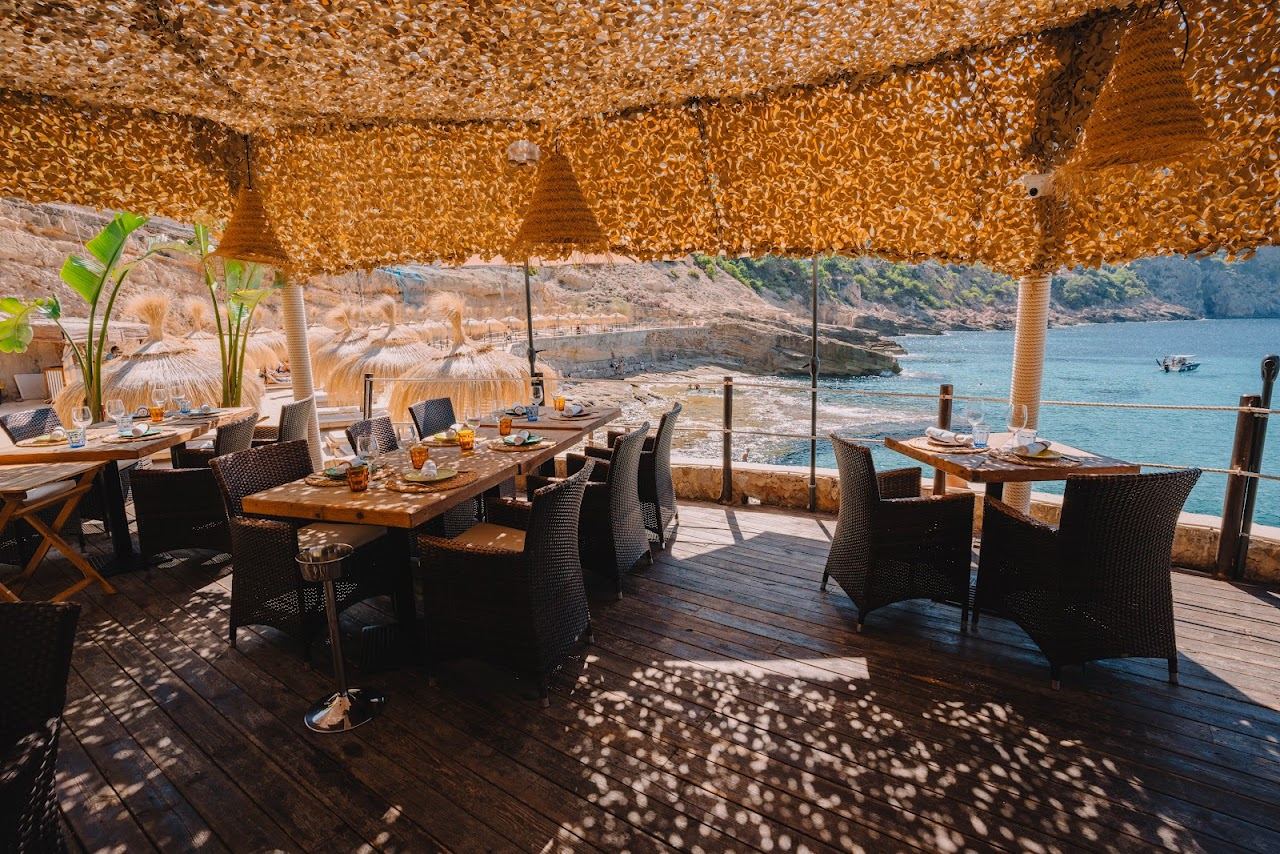 Sun loungers and pool on the rocky clifftop of Gran Folies above the turquoise water of Cala Llamp, Mallorca