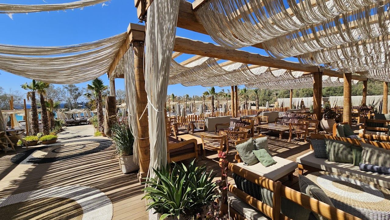 A large modern beach club with rows of sunbeds and a pool above the sea at SantAnna Mykonos