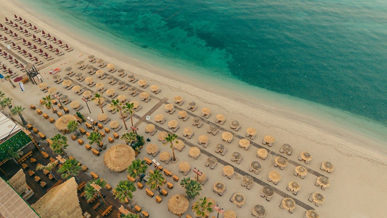 A relaxed city beach bar with sunbeds and a long pier at Bolivar on the Athens coast