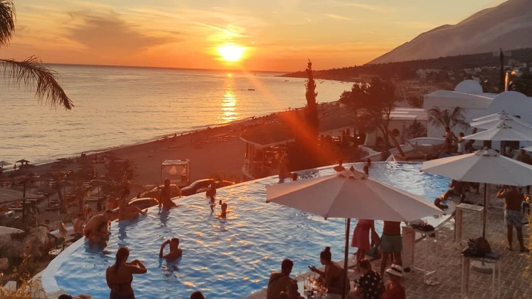 Sunbed rows and umbrellas of Havana Beach Club on the white pebble shore at Dhermi