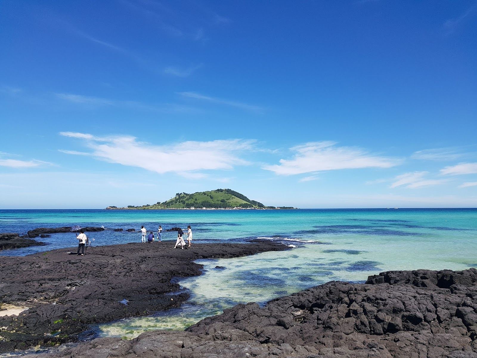 The white shell sand and shallow turquoise water of Hyeopjae beach on the west coast of Jeju with Biyangdo island offshore