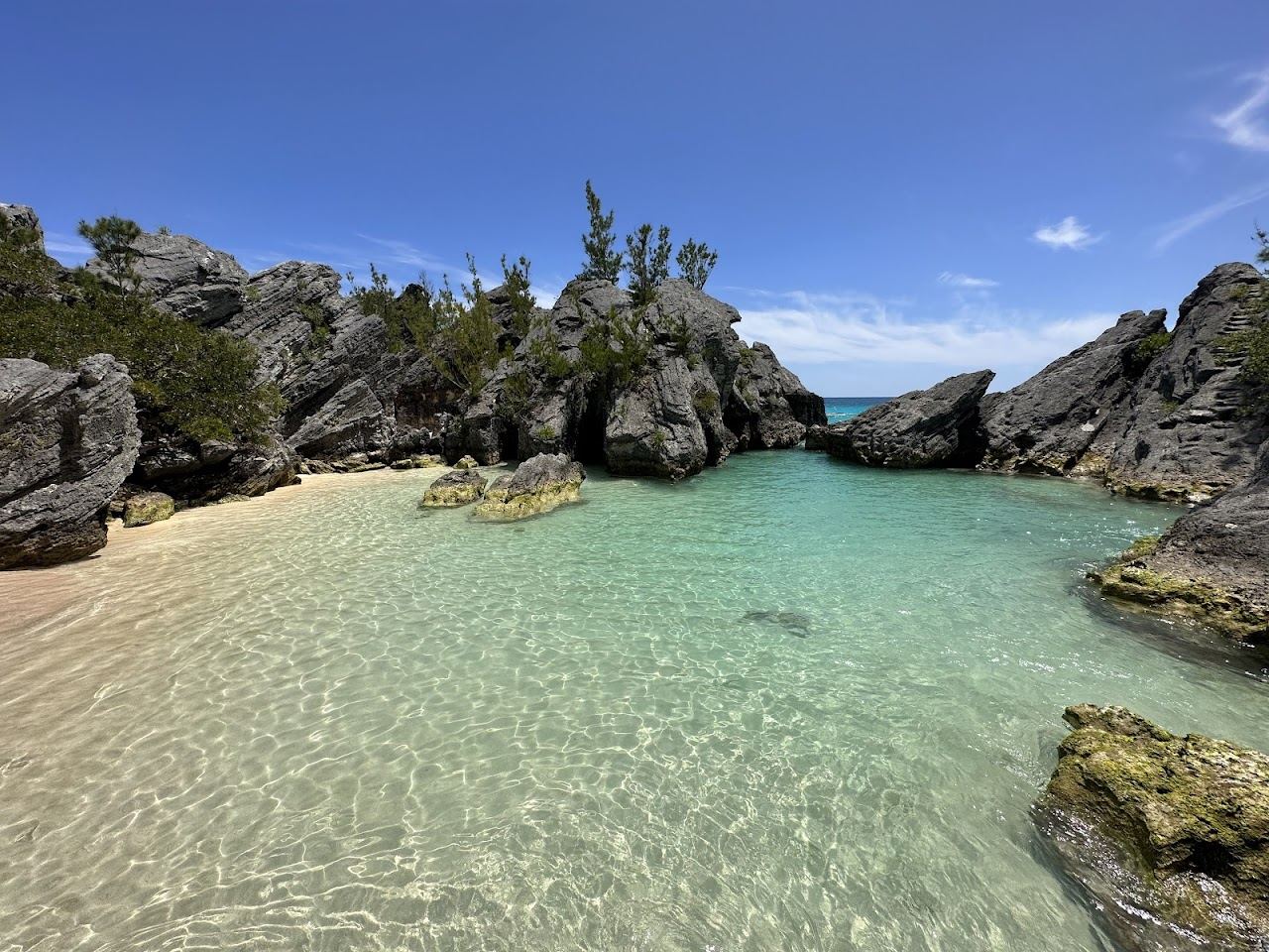 The tiny pink sand lagoon ringed by rock with calm shallow water at Jobsons Cove in Warwick, Bermuda