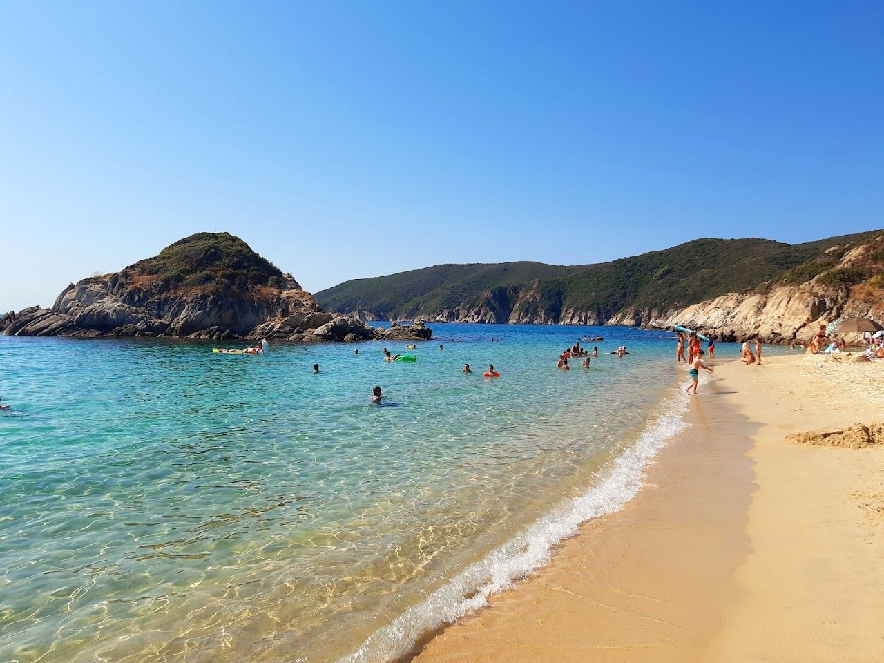 The white gravel shore and bright turquoise sea with rocks at Kalamitsi beach in Lefkada