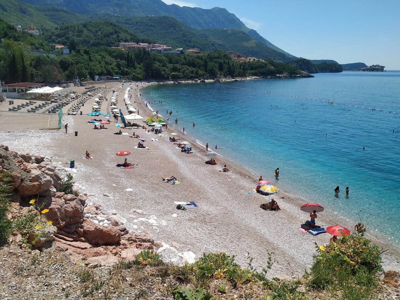 The turquoise cove of Kamenovo beach framed by green headlands near Budva