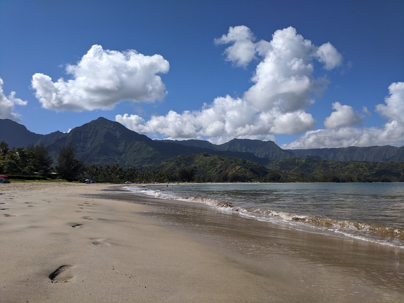 The wide golden crescent of Hanalei Bay under green mountains on Kauai's north shore