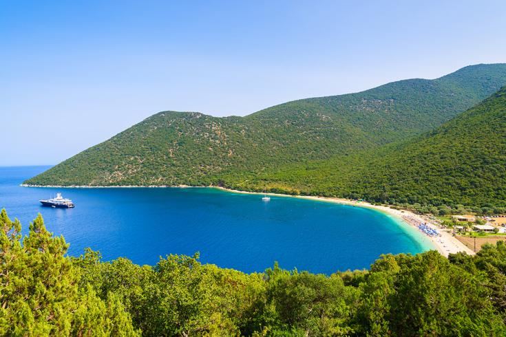 The sheltered green bay and calm clear water of Antisamos Beach near Sami in Kefalonia