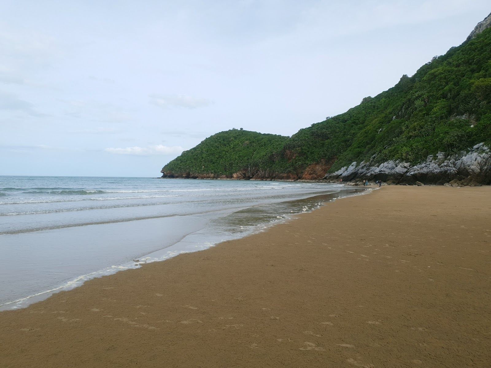 Wide pale sand and calm water below the limestone headland at Khao Kalok Beach south of Hua Hin