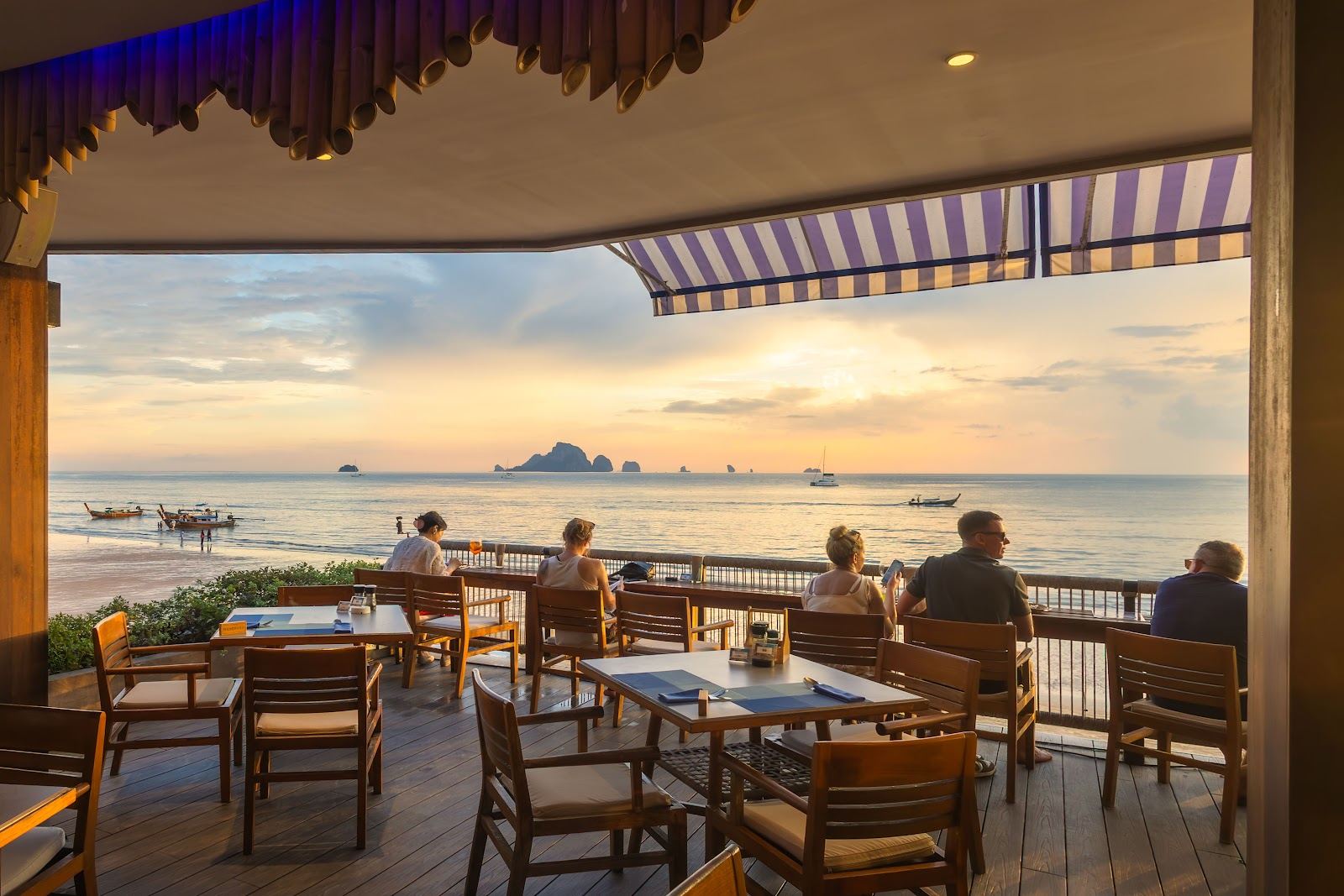 Loungers on Ao Nang sand at a Krabi beach club near sunset