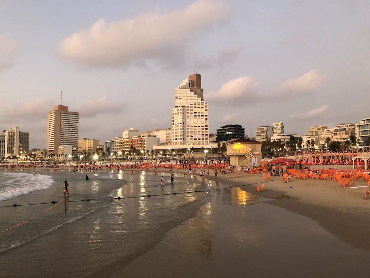 Wide golden sand and swimmers at Gordon Beach in central Tel Aviv with the city skyline behind