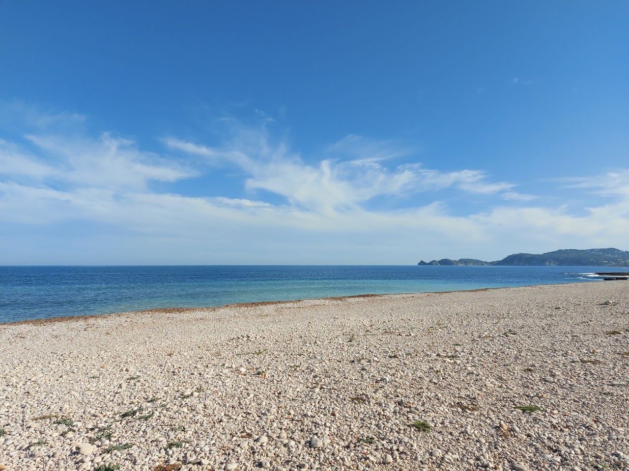 Clear blue water along the flat rock shore of the Primer Montañar in Javea