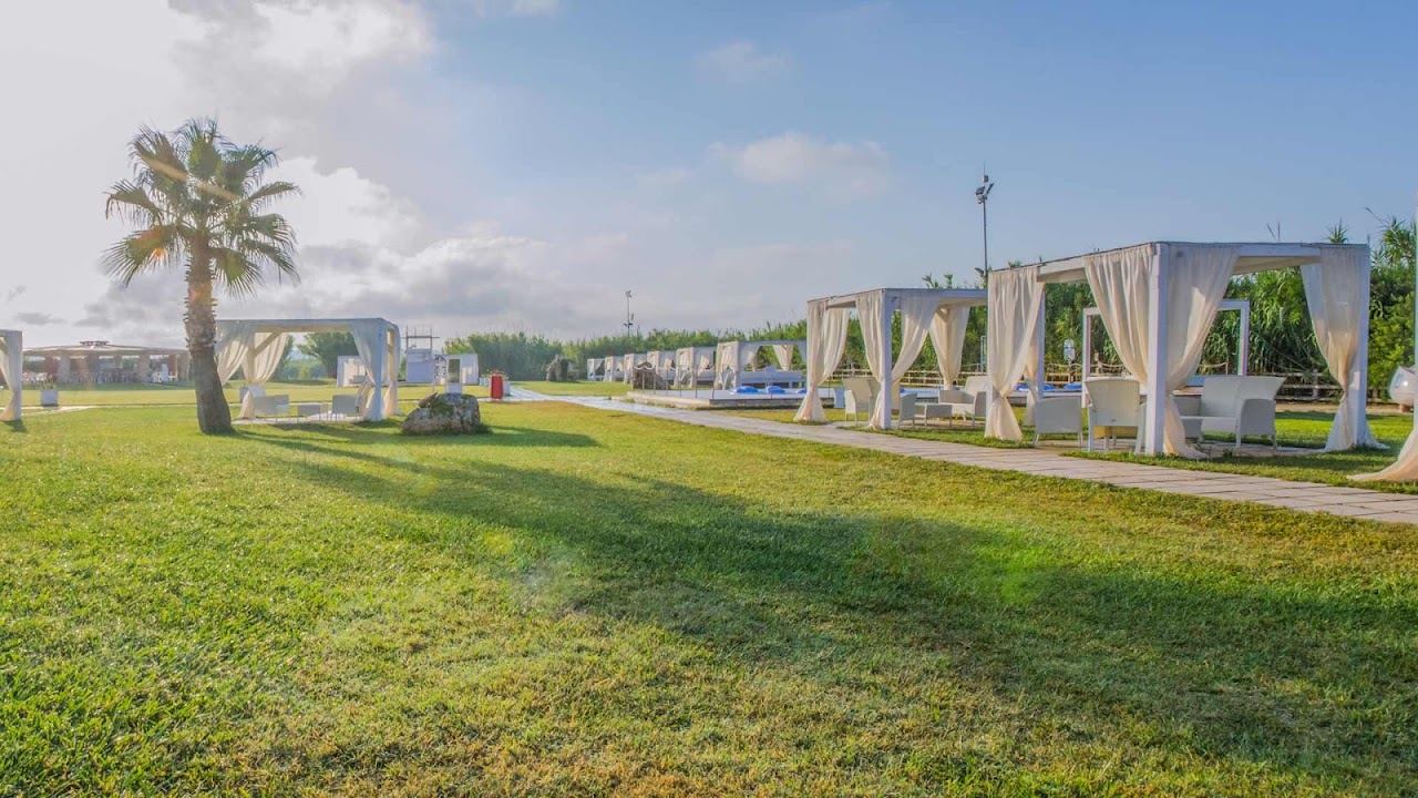 White gazebos and umbrella rows of Le Cinque Vele on the pale sand at Marina di Pescoluse