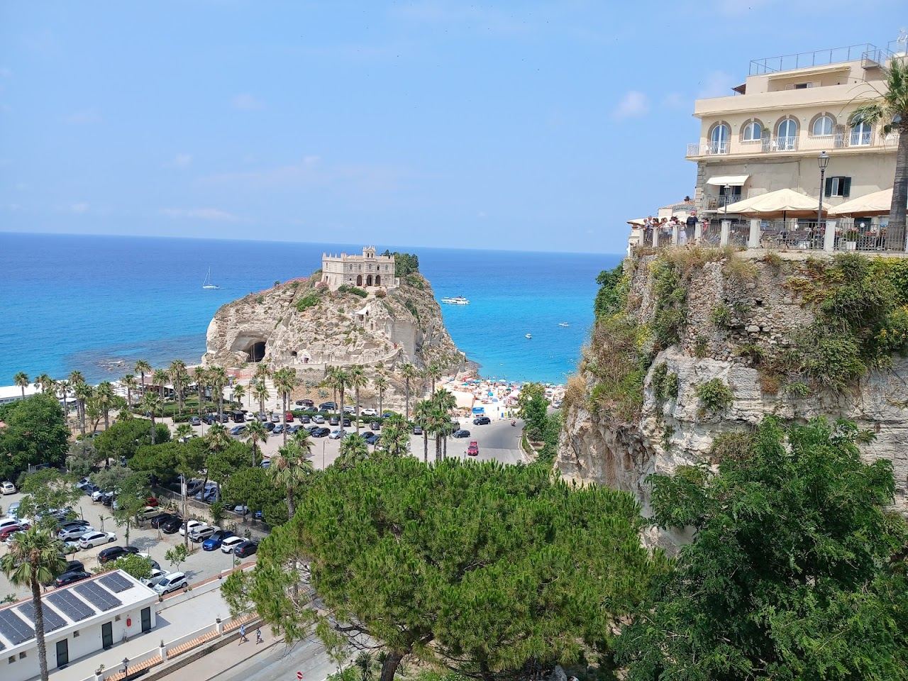 Sunbeds and umbrellas on the small sand cove under the San Leonardo rock at Le Roccette in Tropea