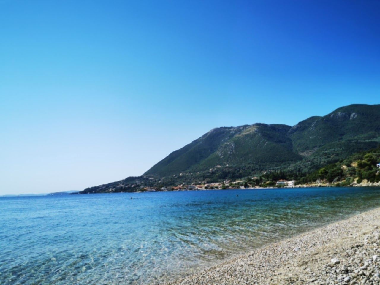 Flat sheltered turquoise water over pale sand on a calm Lefkada bay