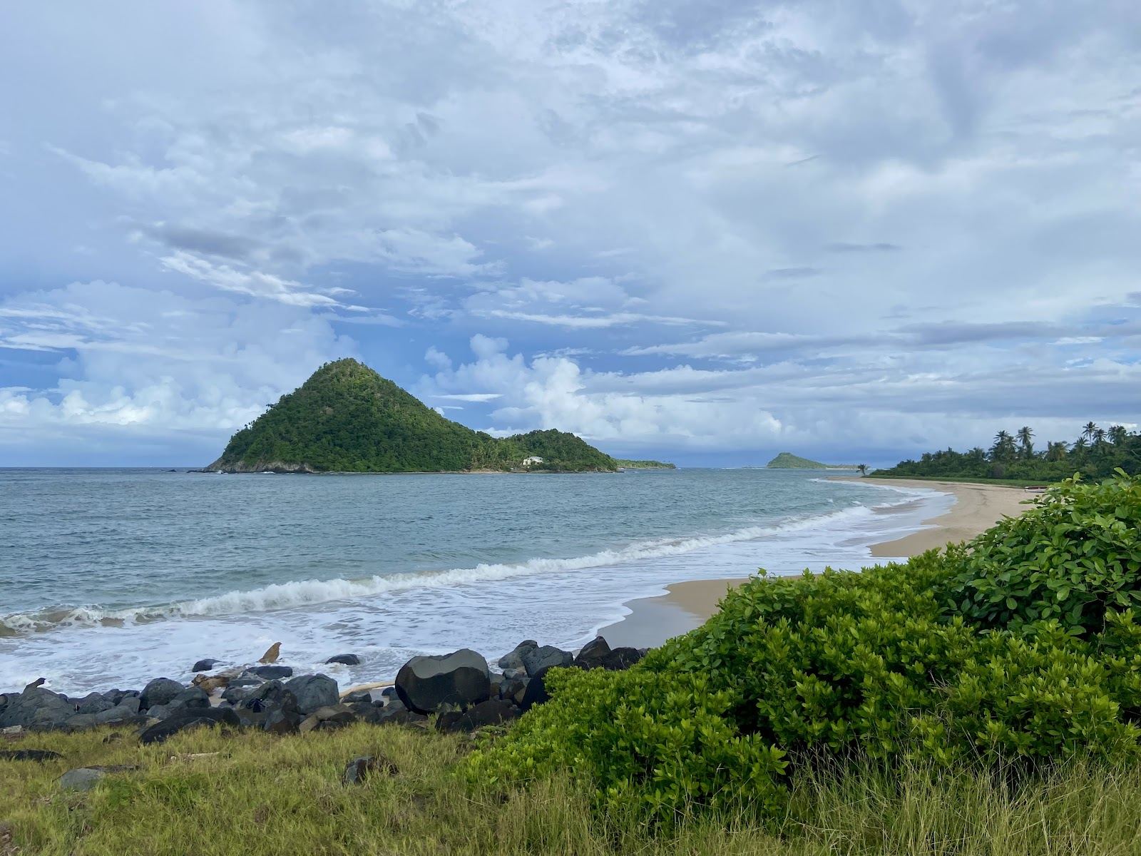 Wild pale sand and Atlantic surf at Levera Beach with Sugar Loaf island offshore on the north coast of Grenada