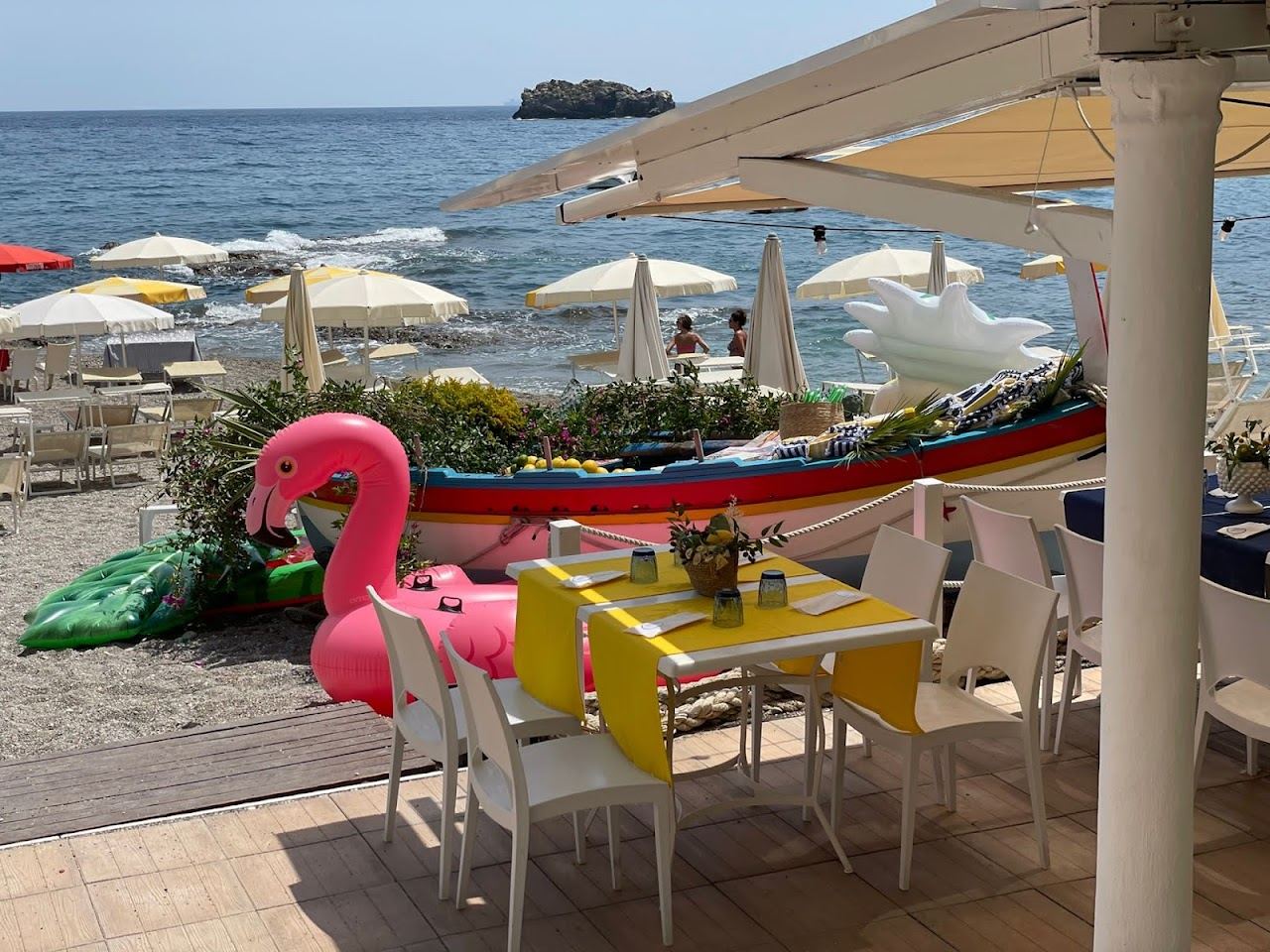 Umbrellas and sunbeds of Lido La Caravella on the shingle shore of Taormina Mare in Sicily