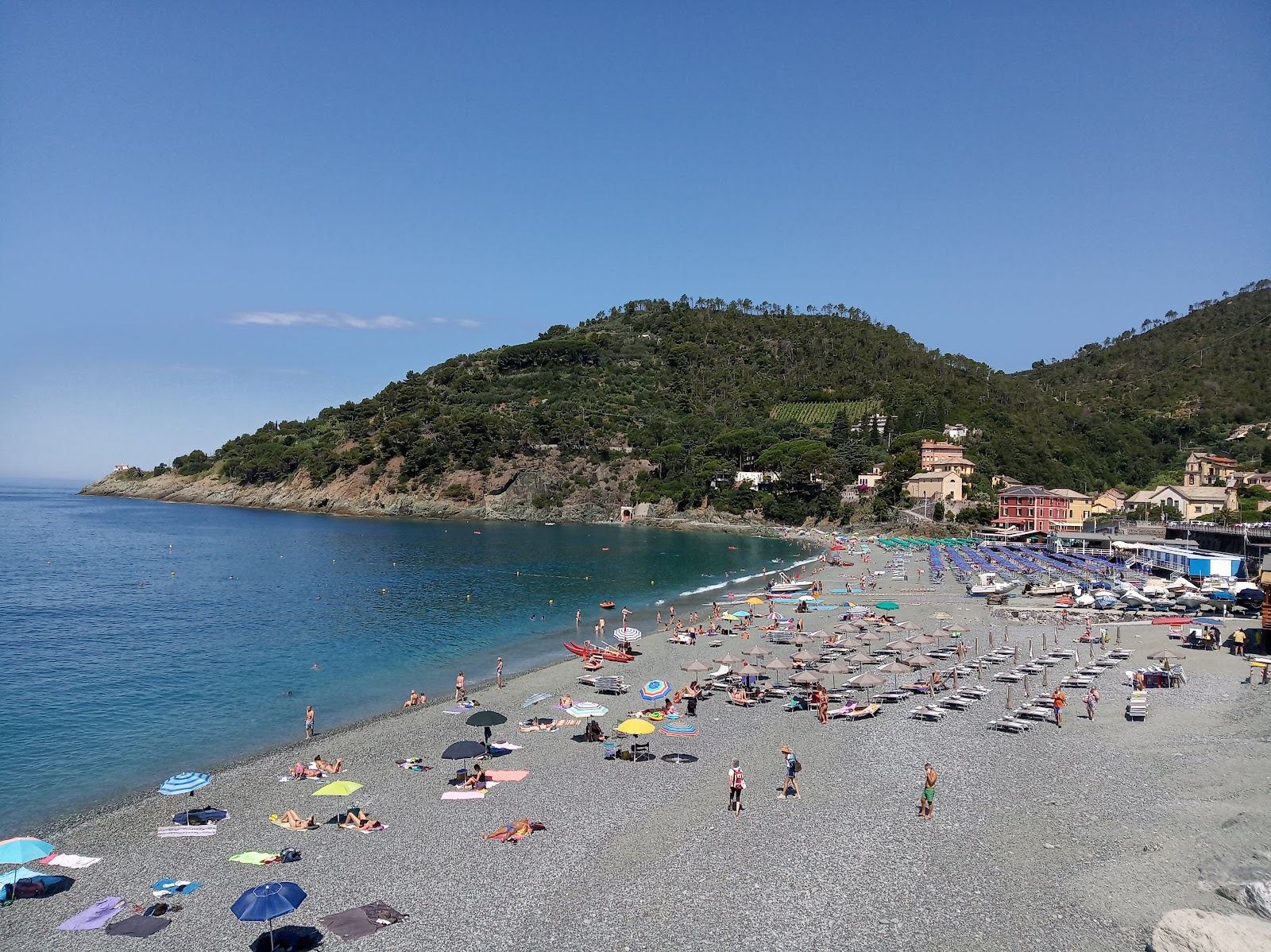 The pale pebble beach and clear water of Bonassola on the Riviera di Levante in Liguria, backed by green hills