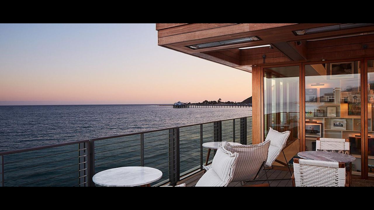 Oceanfront terrace at Little Beach House Malibu at dusk with Malibu Pier in the distance