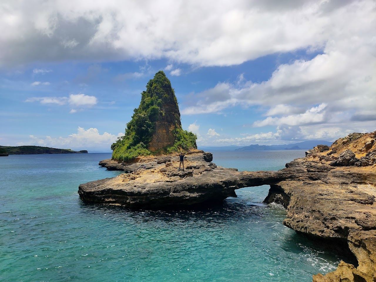 A quiet curve of white sand under red cliffs on the wild south coast of Lombok