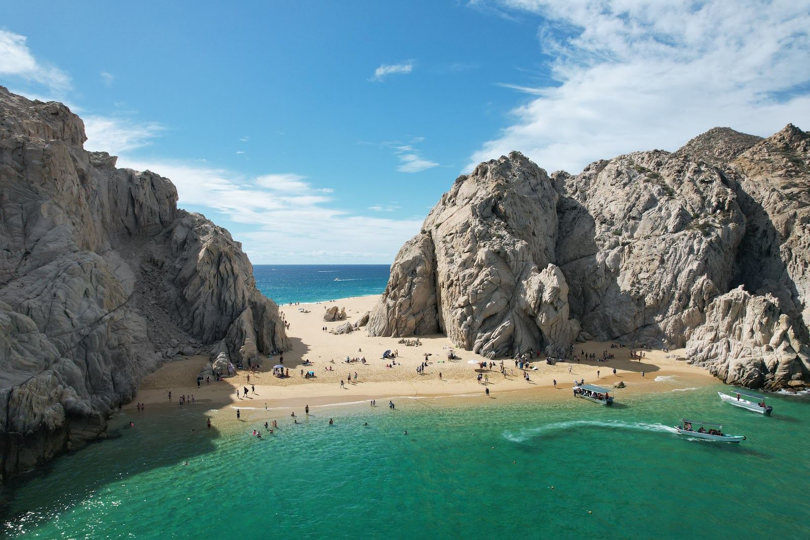 Golden rock formations meeting calm blue water at a secluded cove near Lands End in Los Cabos