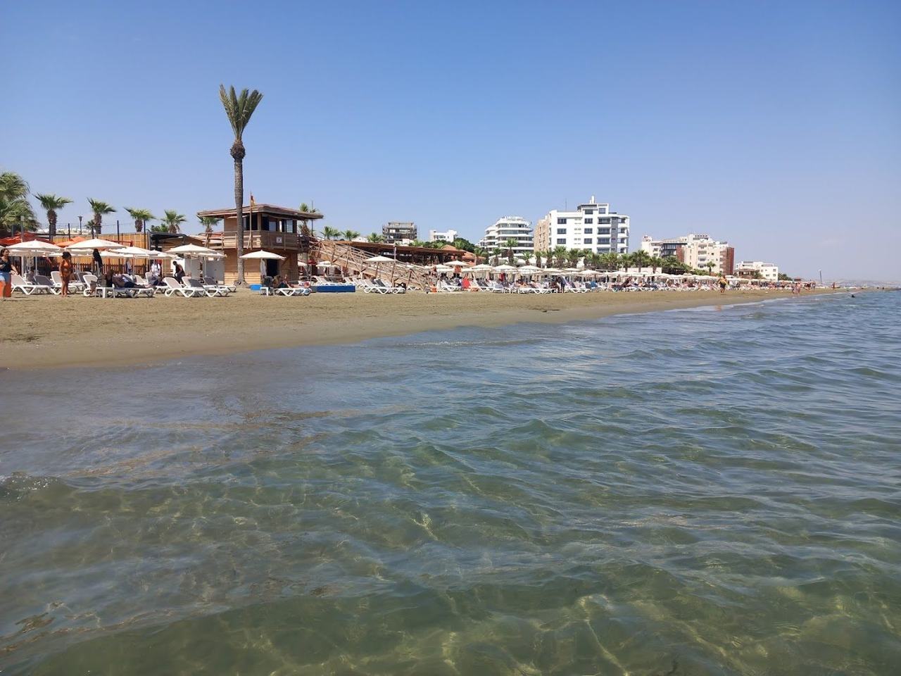 Wide grey gold sand beach lined with beach bars and sunbeds at Mackenzie Beach in Larnaca Cyprus