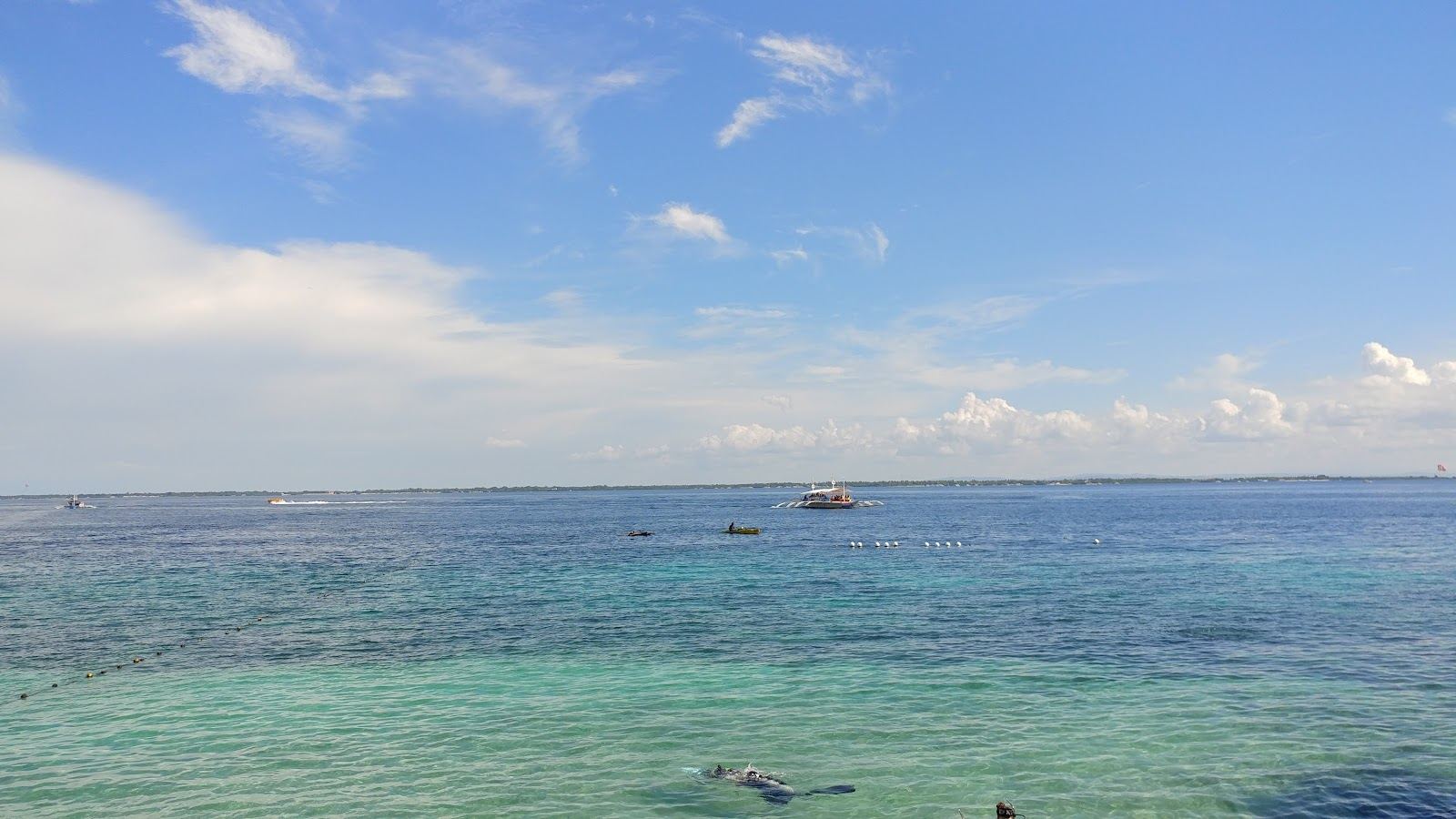 Public sand and calm shallow water on a budget beach day in Mactan.