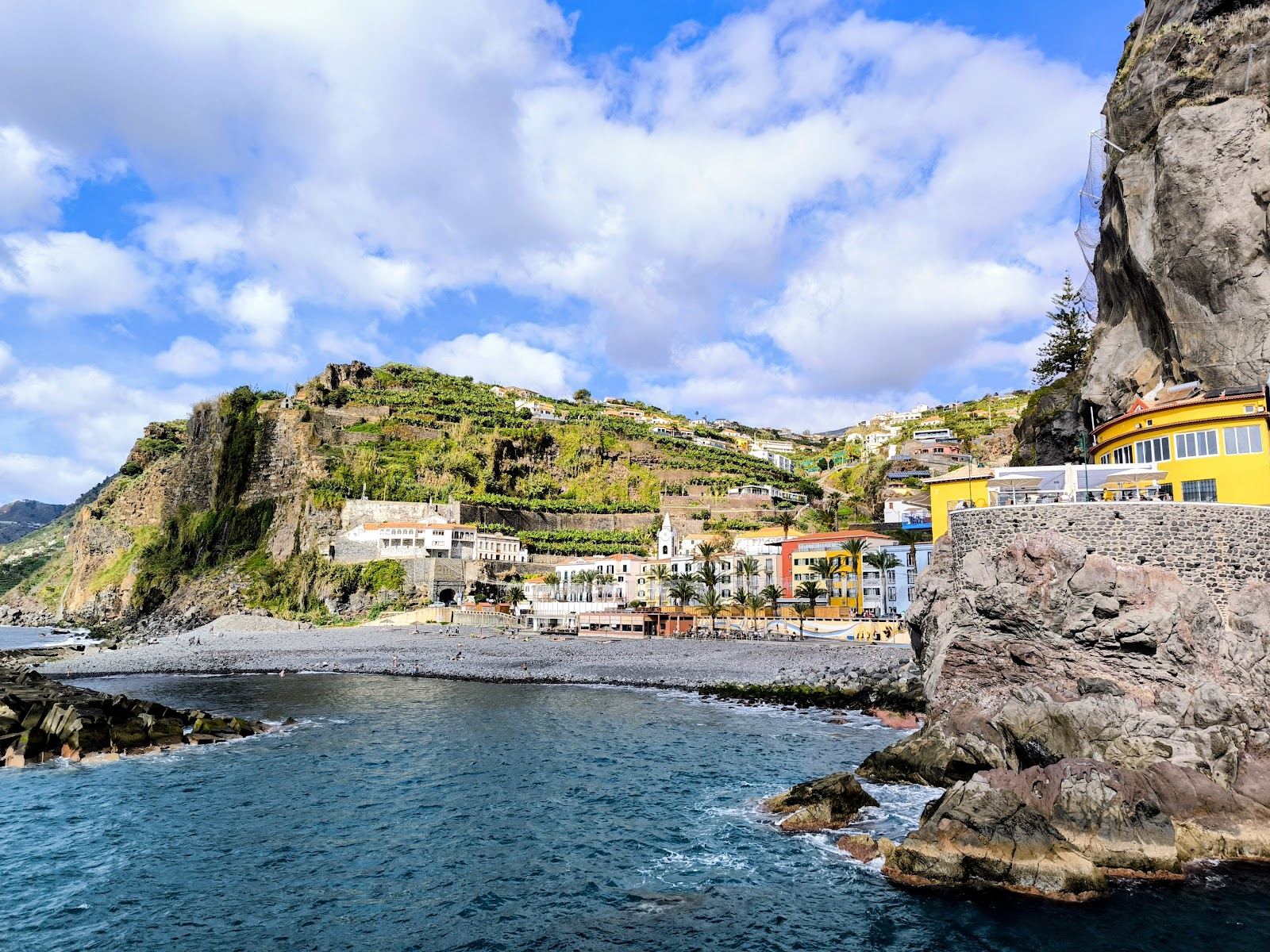 Warm evening light over the seafront and dark pebble shore at Ponta do Sol on the sunny south coast of Madeira