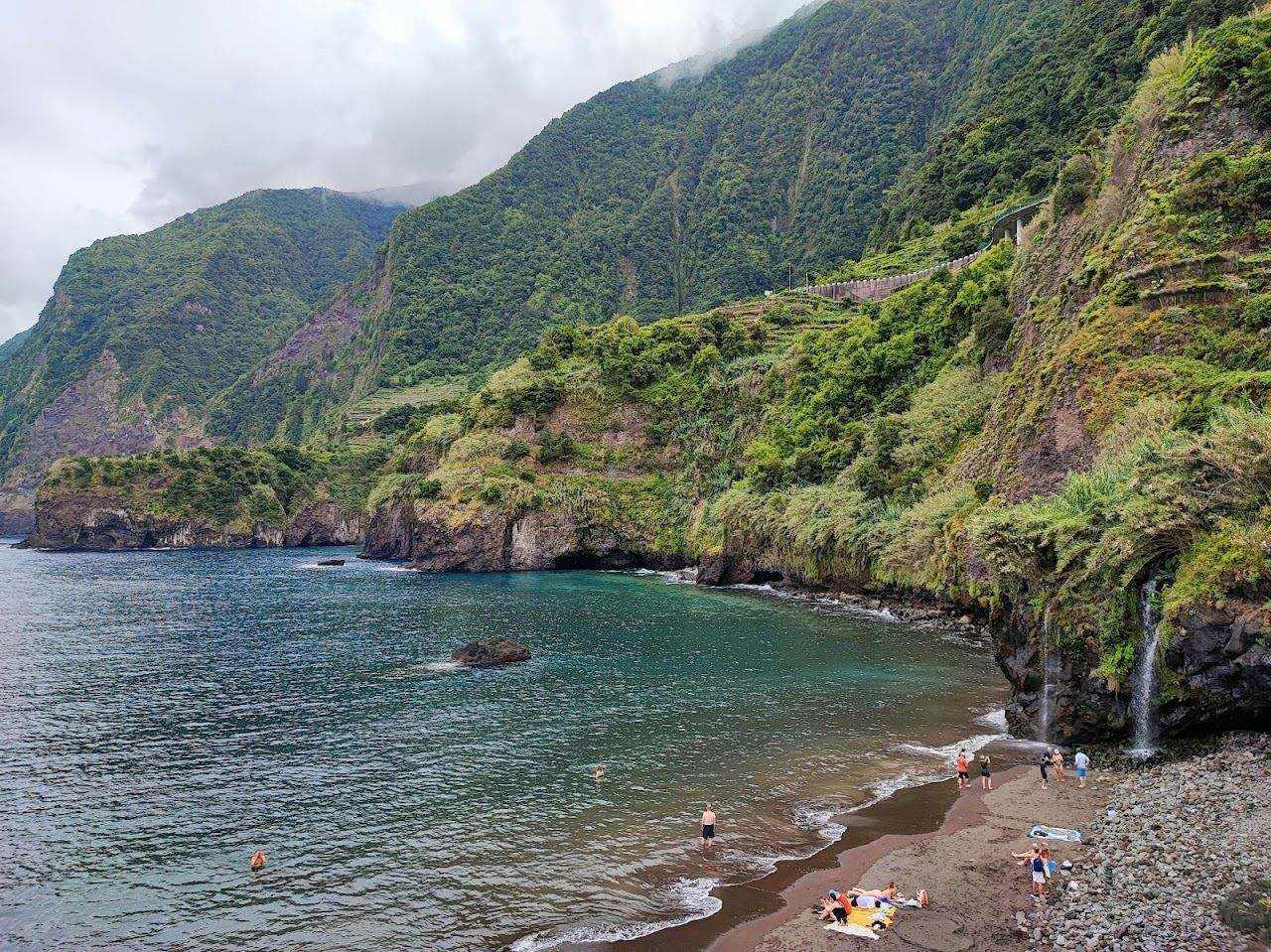 Black volcanic sand beach backed by steep green cliffs on the north coast of Madeira