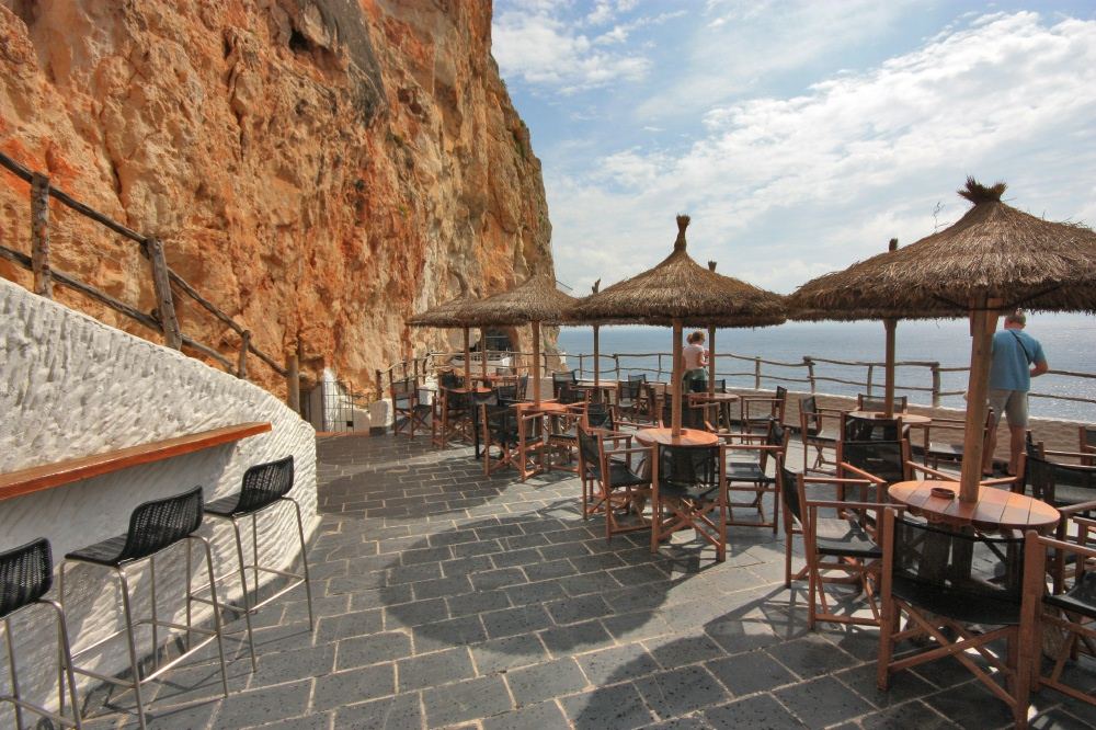 Bar terraces carved into the sea cliff at Cova d'en Xoroi above Cala en Porter in Menorca