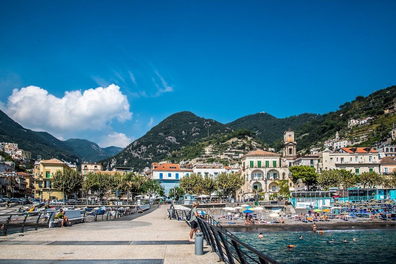Minori beach and seafront promenade below the green hills of the Amalfi Coast