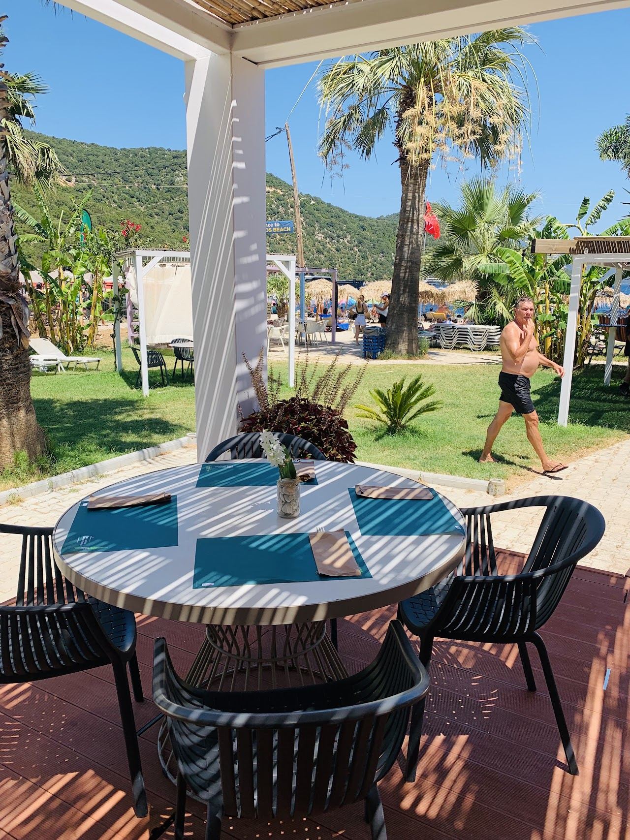 The deck and shoreline seating of Mojito Beach Bar on the white pebbles of Antisamos bay in Kefalonia