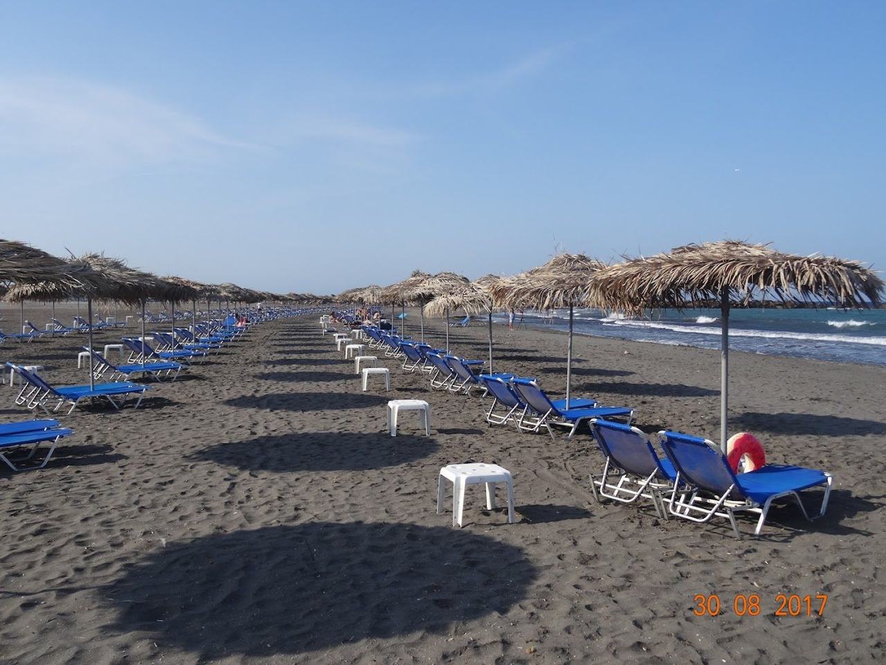 Soft dark sand and shallow calm water at the family beach of Monolithos on Santorini