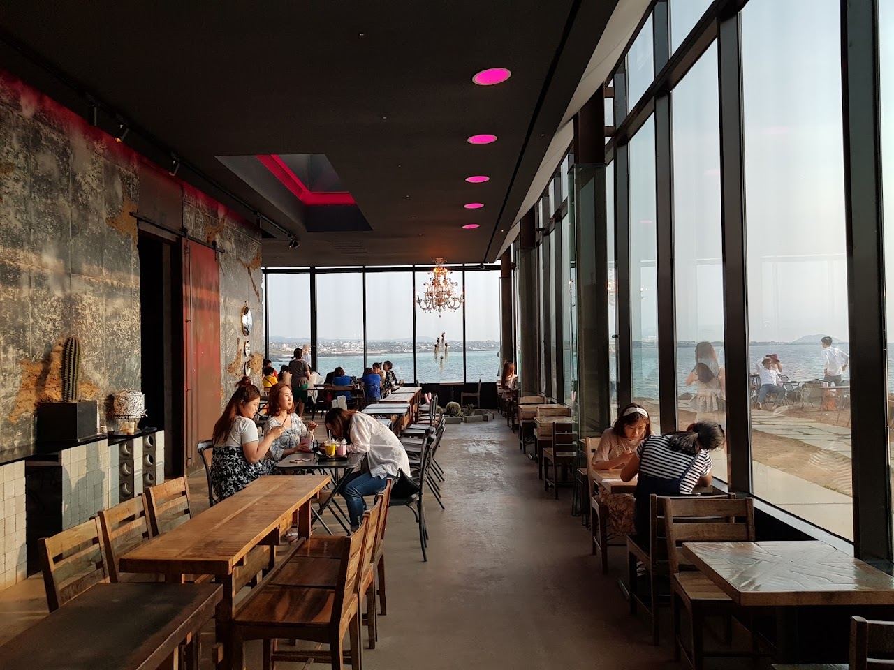 Mirrored glass walls of the Monsant cafe on the volcanic shoreline at Aewol in Jeju