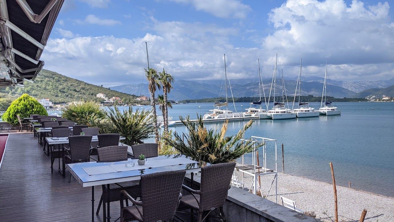 Loungers and umbrellas of Movida Beach on the fine pebble shore of Boka Bay near Tivat