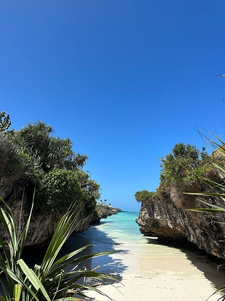 A tiny turquoise cove framed by tall coral cliffs at Mtende beach on the south coast of Zanzibar