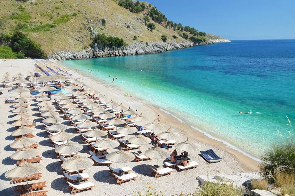 White pebble shore and turquoise water of Llamani beach in its rocky cove south of Himara