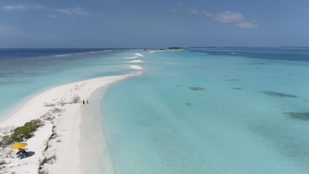 A long white sand beach trailing into a turquoise sandbank at Dhigurah in the Maldives