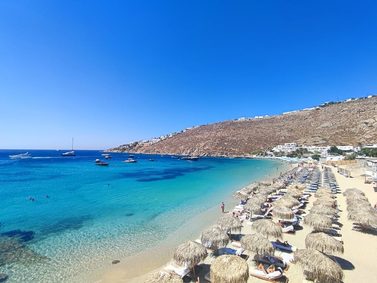 Emerald shallows and fine sand of Psarou Beach, Mykonos, seen from the water line