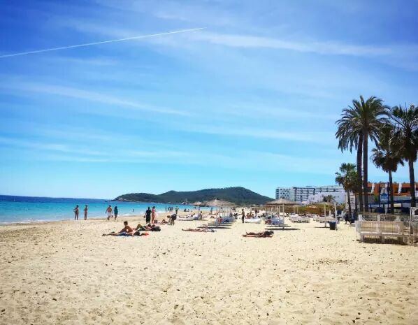 The long flat sweep of pale sand and shallow clear water along Playa den Bossa in Ibiza