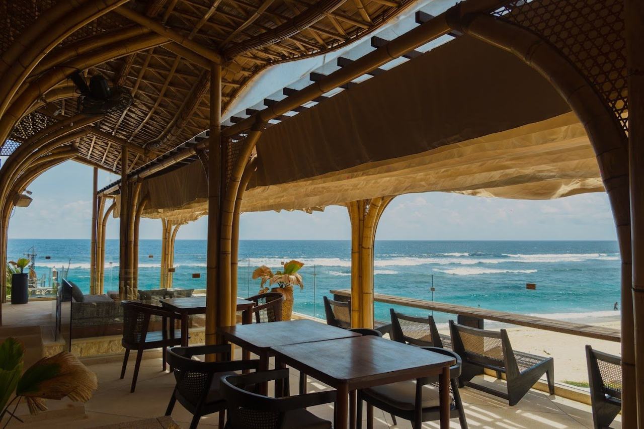 A cliffside beach club with loungers above the white sand of Melasti beach on Bali