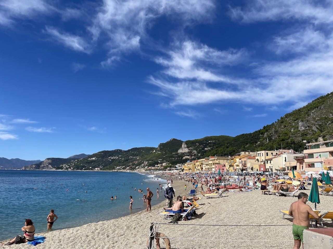 The ochre and rose houses of Varigotti village rising directly behind the sand